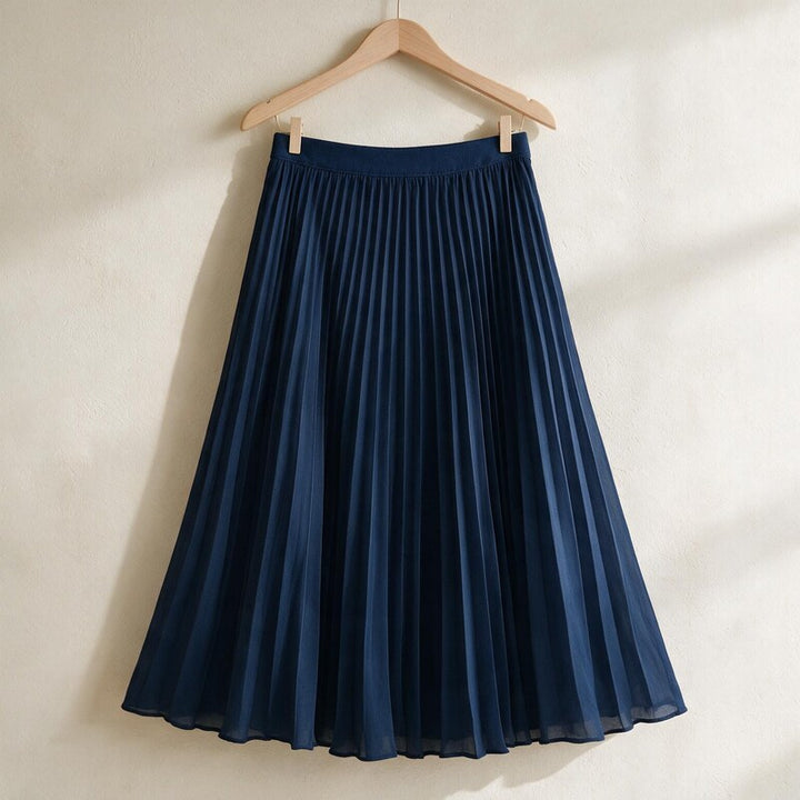 Lucy Melbourne pleated midi skirt in Navy – hanging on a wooden hanger